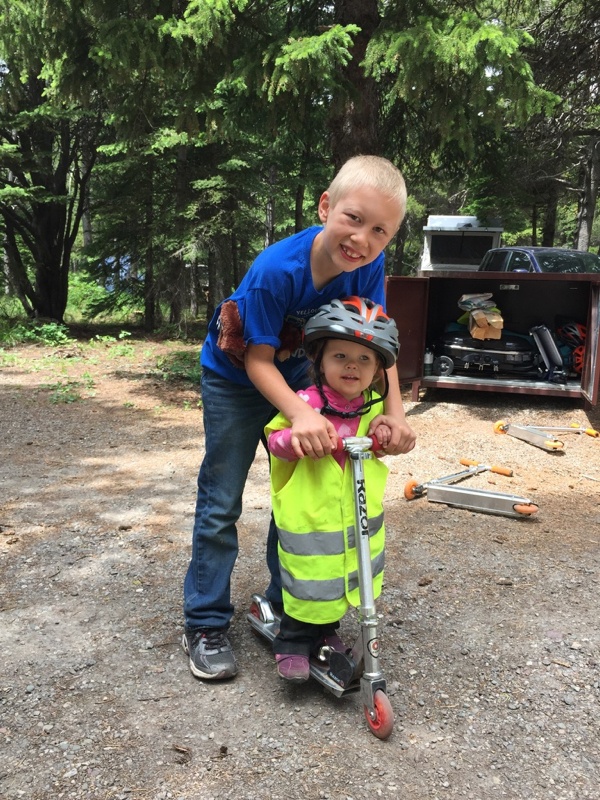 Son Showing sister how to safely scooter with vest and helmet